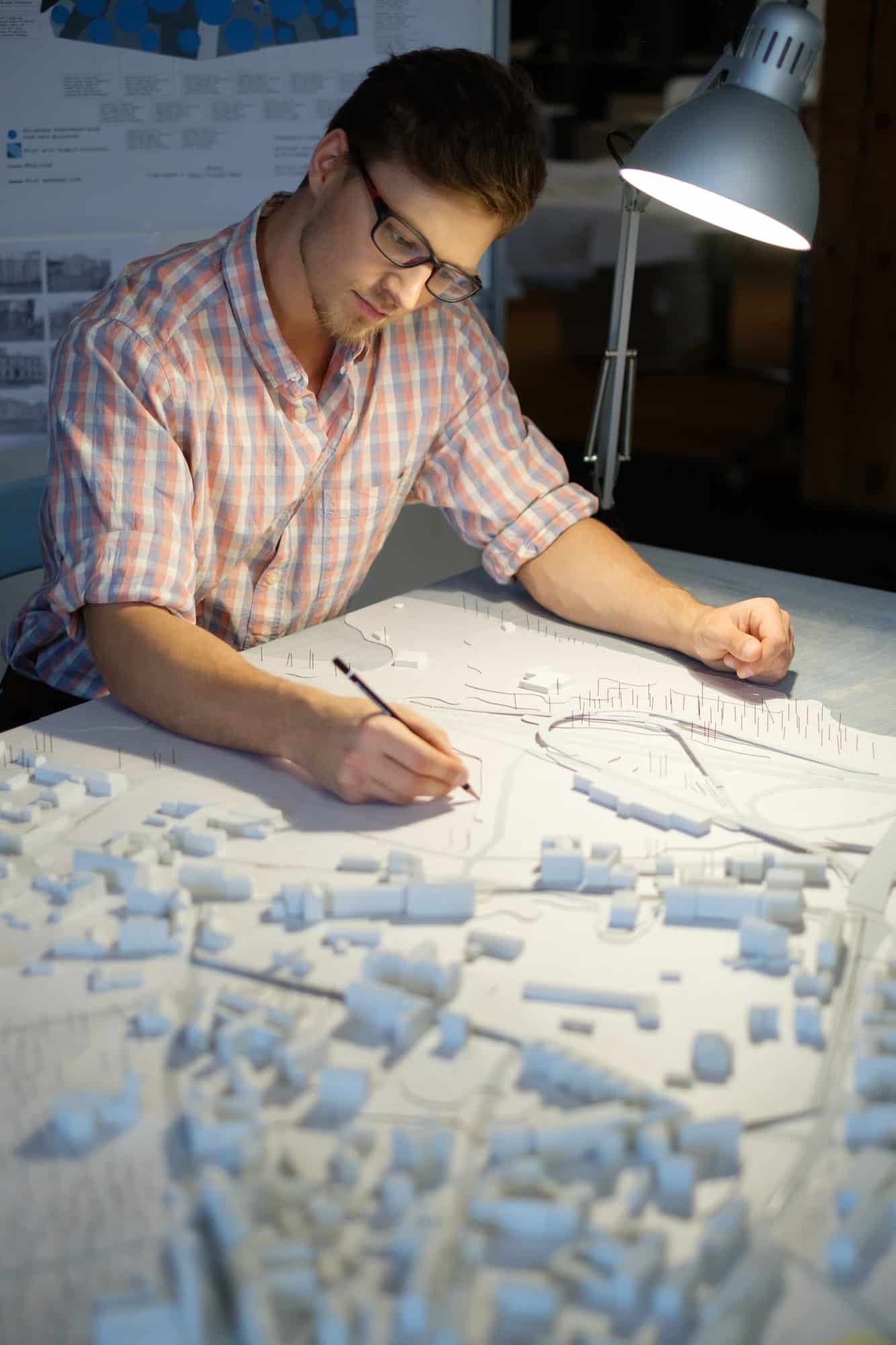 Young architect working on drawing table in architect studio.